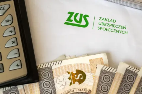 Kalkulator, banknoty i dokument ZUS. Obrazek nawiązuje do tematu zasiłku przedemerytalnego i finansów.