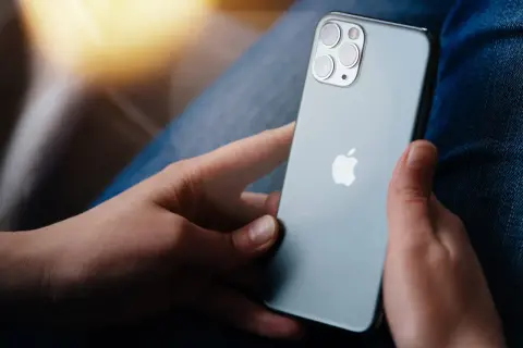Osoba trzyma iPhone'a, zastanawiając się, jak zresetować iPhone do ustawień fabrycznych bez hasła.