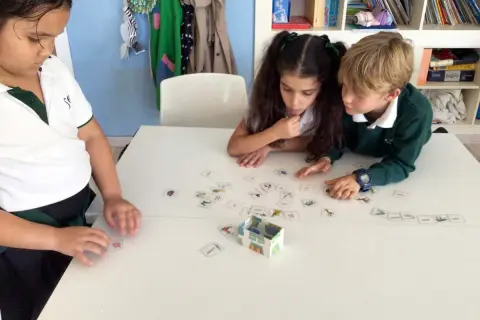 Niños concentrados en juegos de verbos con tarjetas de imágenes.