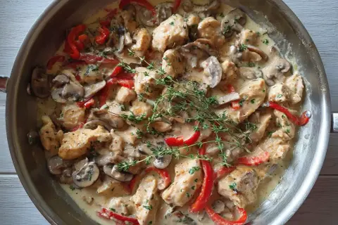 En krämig pepper chicken-panna med saftiga kycklingbitar, champinjoner och röd paprika, toppad med färsk timjan.