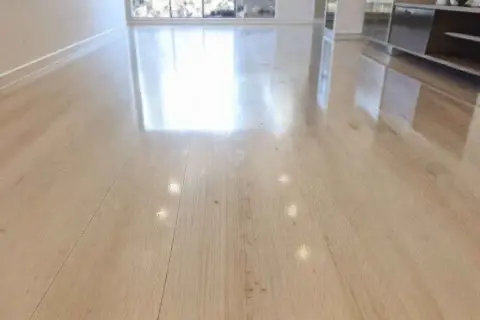 Un sol en bois clair, lustré et sans traces, reflétant la lumière. Un résultat impeccable pour nettoyer carrelage brillant sans trace.