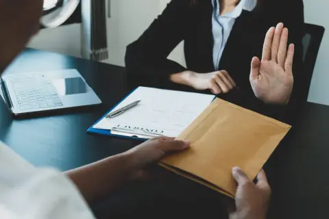 Une main tend une enveloppe, l'autre la refuse. Une scène évoquant le délai réponse inspection du travail licenciement salarié protégé.