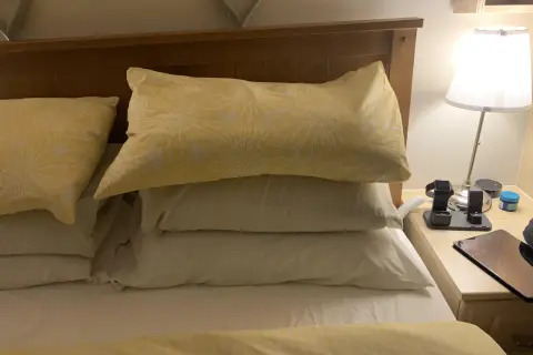A stack of three pillows, one with a yellow sunflower pattern, sits on a bed. Perfect for sleeping with 3 pillows for ultimate comfort.
