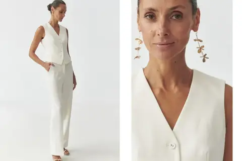 Elegancka biała kamizelka i spodnie tworzą stylowy komplet. Długie, złote kolczyki dodają szyku. Biała kamizelka stylizacje na co dzień i od święta.