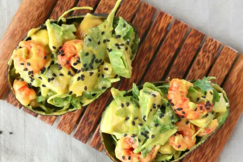 Deliciosa ensalada de langostinos y aguacate, servida en mitades de aguacate y espolvoreada con semillas de sésamo negro.