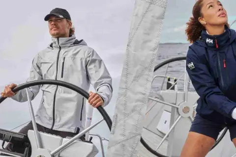 Uomo e donna con abbigliamento tecnico per barca a vela, pronti per navigare.