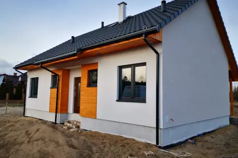 Nowoczesne domy szkieletowe na zgłoszenie, białe z drewnianymi elementami, gotowe do zamieszkania.