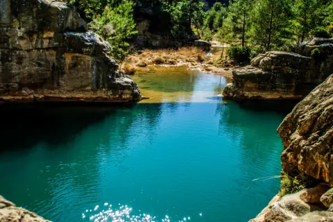 Aguas turquesas de ríos cerca de Zaragoza, rodeadas de rocas y vegetación exuberante. Un rincón natural para descubrir.
