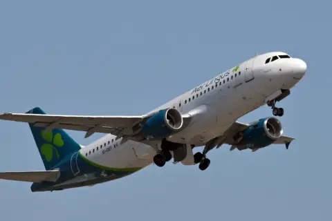 Samolot Aer Lingus z zieloną koniczynką na ogonie wznosi się na błękitne niebo.