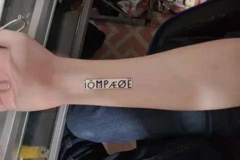 Nowy tatuaż na przedramieniu: ÌÕMPÆØË. Wygląda jak tajemniczy symbol.