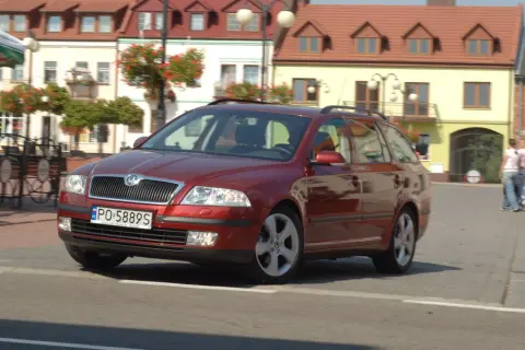 Czerwona Skoda Octavia 2 kombi na ulicy, z widocznymi żarówkami w przednich reflektorach.