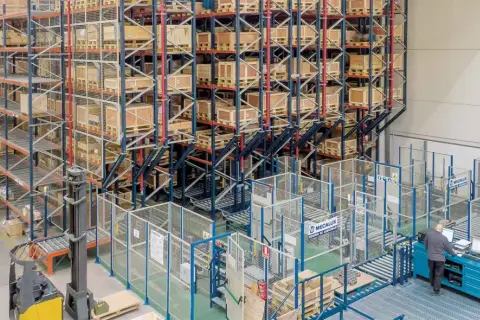 Wysoki regał magazynowy z paletami i wózek widłowy w nowoczesnym centrum logistycznym.