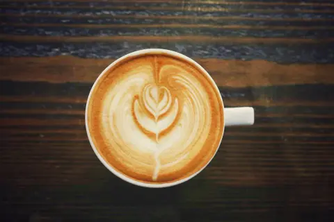 A filiżanka kawy latte z pięknym wzorem na piance. Czy kawa podnosi ciśnienie? Ta pyszna kawa na pewno podniesie Ci nastrój!