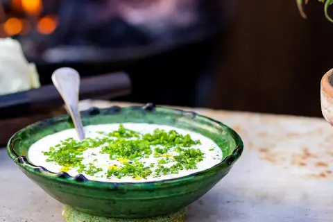 Grönskande skål med krämig ranch dressing, toppad med färska örter. En sked vilar i skålen, redo att servera.