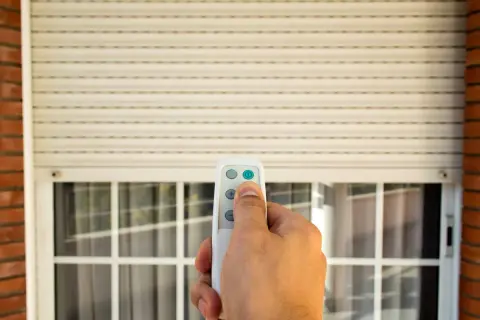 Mano che usa un telecomando per alzare una tapparella elettrica. Utile per capire quanto costa mettere le tapparelle elettriche.