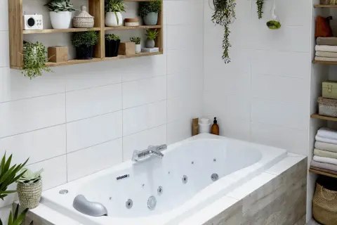 Baignoire d'angle avec robinetterie chromée. La hauteur du robinet baignoire est idéale pour remplir la vasque. Des plantes décorent l'espace.