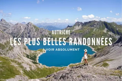 Vue panoramique d'un lac bleu turquoise entouré de montagnes majestueuses en Autriche. Une femme en robe blanche admire le paysage, prête pour un trek.