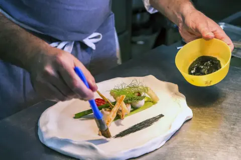 Szef kuchni w restauracji z gwiazdką Michelin precyzyjnie dekoruje danie.