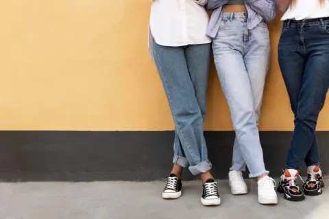 Trzy dziewczyny w szerokich jeansach i modnych sneakersach. Idealne inspiracje, jakie buty do szerokich spodni jeansowych.