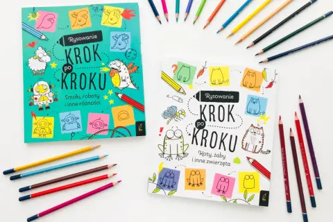 Dwie książeczki "Rysowanie krok po kroku" dla dzieci, jedna ze smokami i robotami, druga z kotami i żabami, otoczone kolorowymi kredkami.
