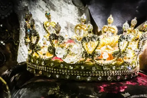 Korona zdobiona klejnotami, symbol bogactwa i władzy, przypomina o globalnym wydobyciu złota.