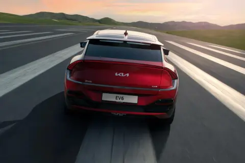 Röd Kia EV6 kör på en väg med vita linjer. En besiktning av spindelleder kan vara aktuell om det finns glapp.