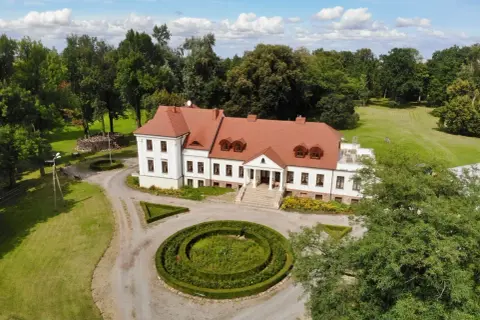 Piękny dwór stary Chotów otoczony zielenią, z zadbanym ogrodem i krętą ścieżką.