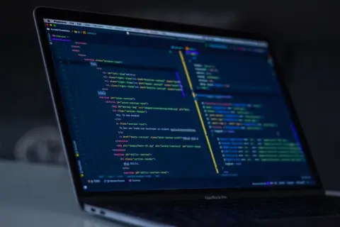 Code sur un écran d'ordinateur portable, affichant du code HTML et JavaScript, avec des éléments de développement web, comme un `EventEmitter` dans Angular.
