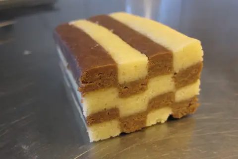 En bit av ett hembakat schackrutemönstrat kex med choklad och vaniljsmak.