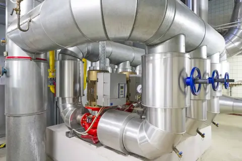 Detailaufnahme einer Anlage mit großen Rohren, Pumpen und Ventilen, die an ein mini blockheizkraftwerk angeschlossen sind.