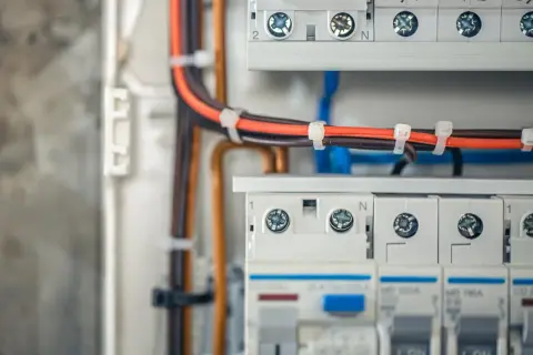 Szczegółowy widok podłączenia rozdzielnicy elektrycznej. Widać kable, bezpieczniki i zaciski.