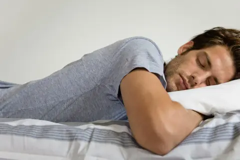 Hombre durmiendo boca abajo, con la cabeza apoyada en una almohada. Se pregunta: "porque sudo mucho cuando duermo soy hombre".