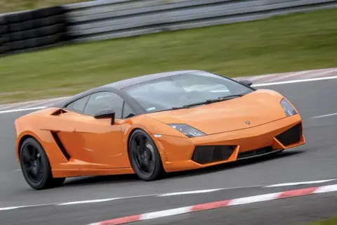 Pomarańczowe Lamborghini pędzi po torze wyścigowym, zostawiając za sobą smugę prędkości.
