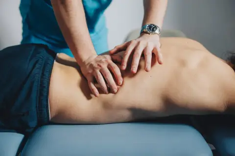 Mains d'un thérapeute massant le dos d'un patient, soulageant un muscle froissé.