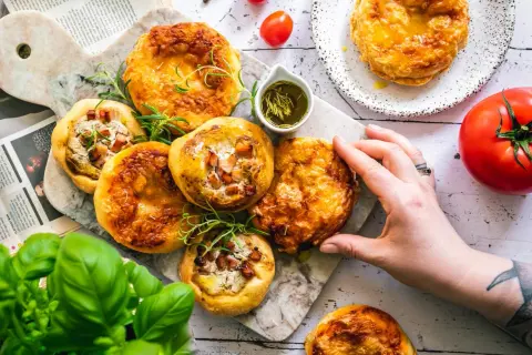 Mini tarty z boczkiem i serem, podane z oliwą z oliwek i ziołami. Zdrowe tłuszcze produkty na talerzu.