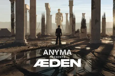 Mężczyzna stoi przed ruinami starożytnych kolumn, patrząc na gigantyczny posąg. Anyma Presents ÆDEN – zapowiedź koncertu.