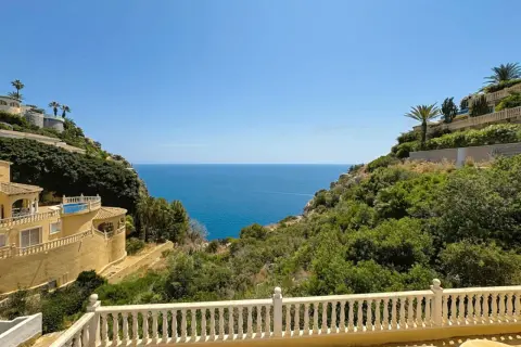 Vista desde una terraza con barandilla blanca hacia el mar azul, con villas en laderas verdes. La puerta del mar San José se abre a un paisaje idílico.