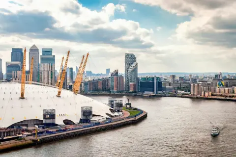 En linbana London över Themsen, med O2 Arena och skyskrapor i bakgrunden.