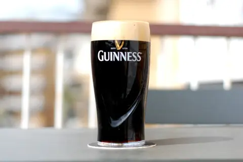 Un bicchiere di birra scura irlandese Guinness, con la sua iconica schiuma cremosa, pronto per essere gustato.