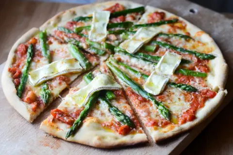 Pyszna pizza ze szparagami i serem brie, z sosem pomidorowym i ciągnącym się serem. Idealna na wiosenny obiad.