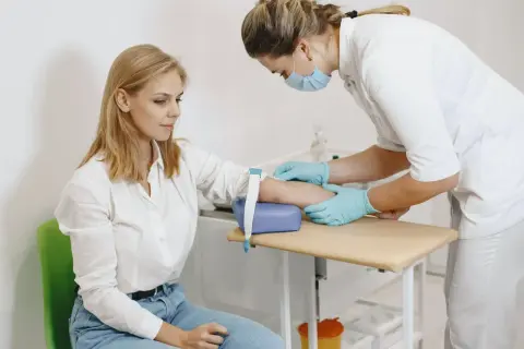 Pielęgniarka pobiera krew, a pacjentka ma lekki siniak po pobraniu krwi.