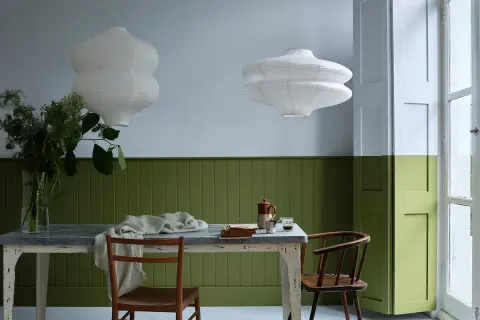 Tavola apparecchiata con sedie in legno, lampade bianche e pareti bicolore: un esempio di eleganti verde oliva abbinamenti.