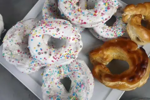 Biscotti a ciambella con glassa bianca e zuccherini colorati, pronti per essere gustati. La glassa per biscotti che si asciuga subito li rende perfetti.