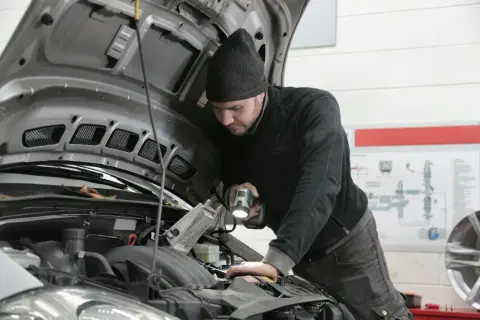 Mechanik z latarką bada silnik 1.9 TDI.