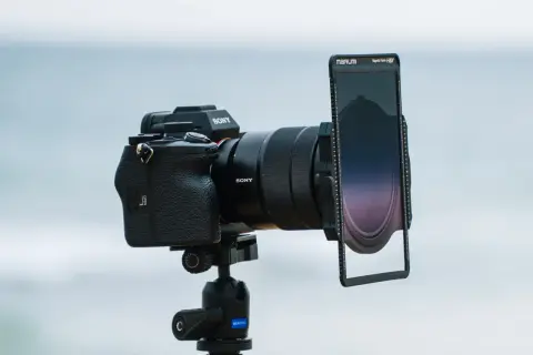 Aparat Sony z obiektywem i uchwytem na filtry do zdjęć. Tło rozmyte, morskie.