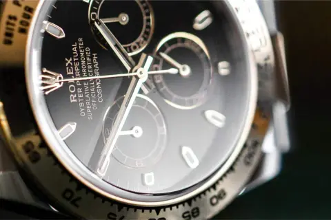 Primer plano de un Rolex Daytona con esfera negra y cristal hesalite. Los detalles del cronógrafo y la inscripción son visibles.