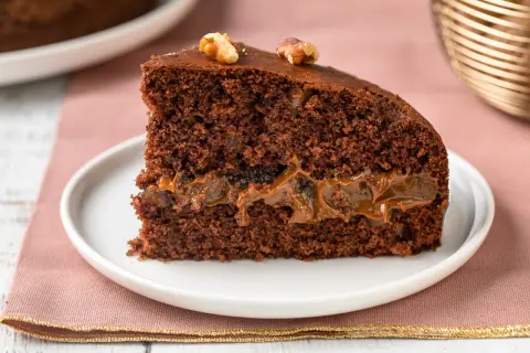 Una fetta di torta al cioccolato con ripieno di caramello e noci, perfetta tra i dolci per le feste.