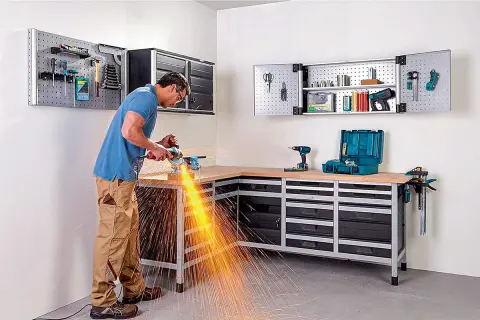 Un homme utilise une meuleuse d'angle dans son atelier bien rangé, créant un spectacle d'étincelles vives.