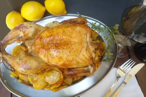 Un capón asado, jugoso y dorado, servido con patatas y limones. ¡Un festín para los sentidos!