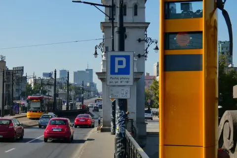 Żółty fotoradar na moście, obok znaku parkingu. Zastanawiasz się, po jakim czasie przychodzi mandat z fotoradaru?